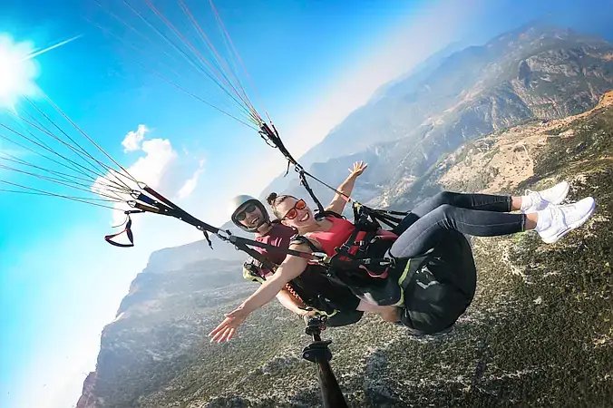 Two people tandem paragliding soaring above stunning natural landscapes, surrounded by mountains and open sky — A perfect experience for adventure seekers and nature lovers.