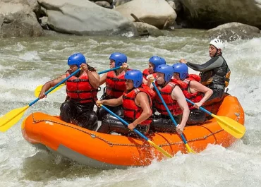 Group of adventurers White-Water Rafting down river rapids, paddling together through splashing waves on a fast-flowing river. A perfect action packed group thrill!