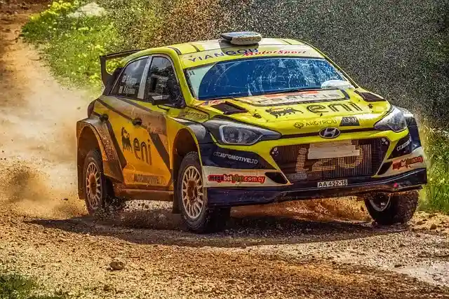 Rally car driving fast on a rugged off-road terrain track, kicking up dust and showcasing high-performance driving. Perfect adrenaline activity for thrill seekers.